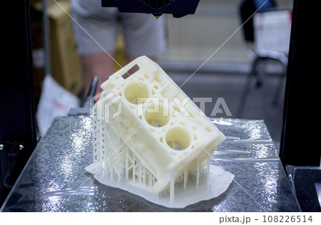 Prototype of car engine printed on 3D printer from molten white plastic on working surface 3D printer. Three-dimensional model. Additive progressive modeling technology. Modern new printing industry. Prototype of car engine printed on 3D printer from molten white plastic on working surface 3D printer. Three-dimensional model. Additive progressive modeling technology. Modern new printing industry. 108226514