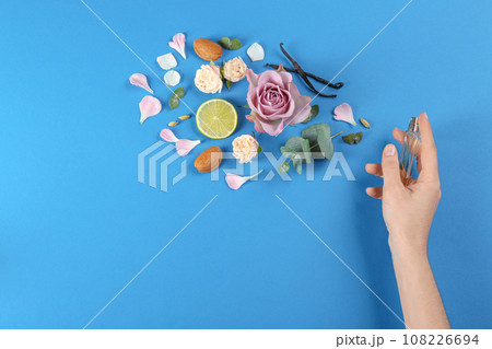 Woman with perfume. Fragrance composition, flowers and lime on blue background, top view Woman with perfume. Fragrance composition, flowers and lime on blue background, top view 108226694
