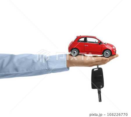Man holding key and miniature automobile model on white background, closeup. Car buying 108226770