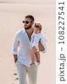 A stylish man with his baby in his arms. A small child in the arms of his father. A beautiful portrait of a child in the arms of his father. Family photo. Dad hugs the baby. 108227541