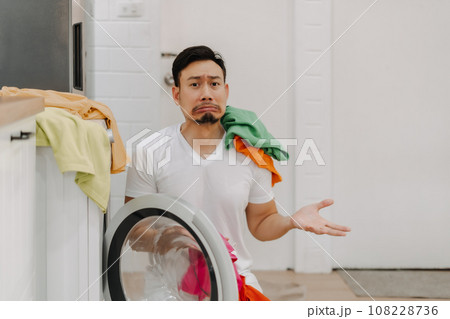 Funny crying man husband thrown with pile of clothes on his face to be washed. 108228736