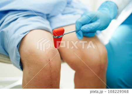 Asian doctor knock on knee reflex nerve for check and treatment senior patient in hospital. 108229368