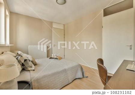a bedroom with a bed, desk and mirror on the wall in front of the room is very light brown a bedroom with a bed, desk and mirror on the wall in front of the room is very light brown 108231102