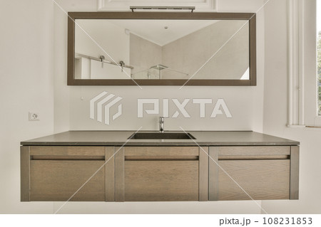 a bathroom with a mirror on the wall above it and a sink in the center of the room next to the window 108231853