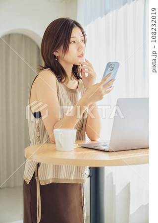 スマホとパソコンで仕事をする女性 108232019