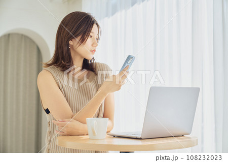 スマホとパソコンで仕事をする女性 108232023