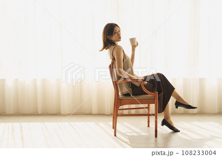 窓際でコーヒーを飲む女性 108233004