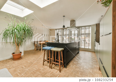 a kitchen and dining area in a house with wood flooring, white walls and skylights above the windows 108233254