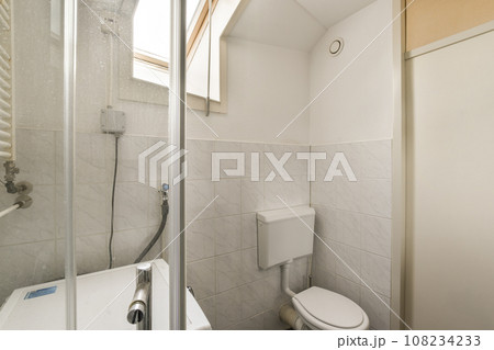 a bathroom with a toilet and shower stall in the corner, as seen from the inside looking into the door 108234233