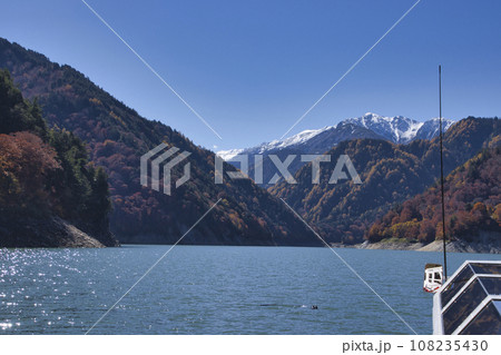 黒部ダム（黒四）　遊覧船ガルベから見る冠雪した赤牛岳との美しい三段紅葉　富山県立山町 108235430