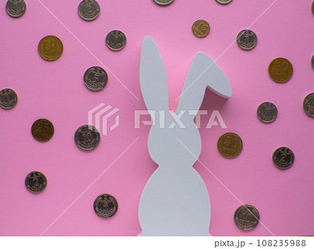 White Easter bunny surrounded by coins on pink background. White Easter bunny surrounded by coins on pink background. 108235988