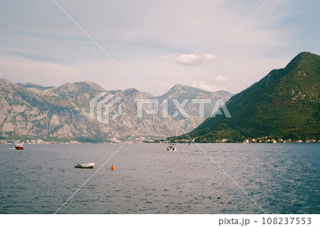 Boats float in the bay against the backdrop of a green mountain range 108237553
