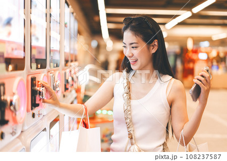 Young adult asian woman play gashapon at game center indoors department store. 108237587
