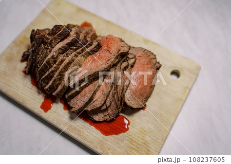 Roast beef slices with blood lie on a wooden cutting board on the table. Top view 108237605