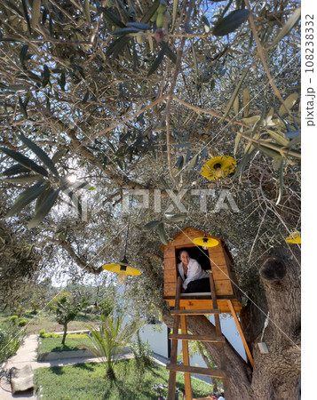 Smiling girl sitting in a wooden treehouse 108238332