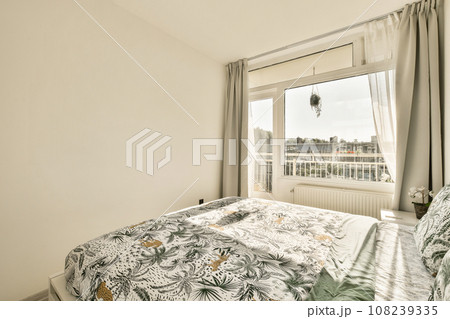 a bed in a bedroom with a view out to the city below and an open window that looks out onto the street a bed in a bedroom with a view out to the city below and an open window that looks out onto the street 108239335