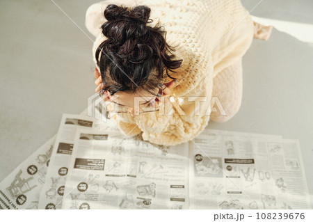 床に座って新聞を読む女性 108239676