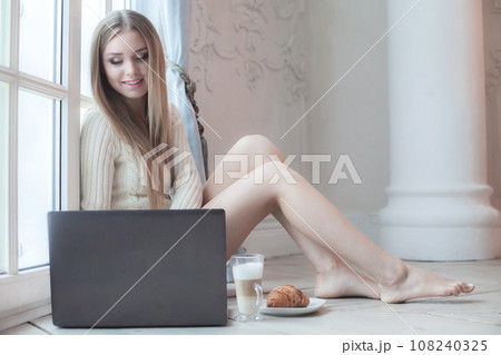 Portrait of young adult woman using laptop and drinking coffee indoor Portrait of young adult woman using laptop and drinking coffee indoor 108240325