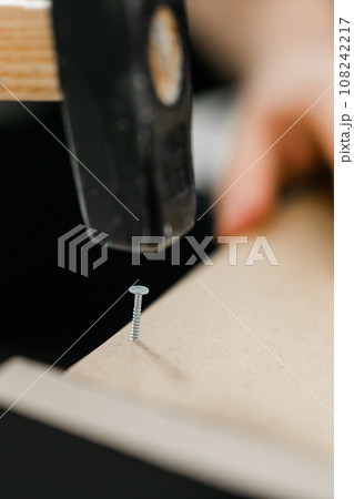 Hammering a nail into wooden board close-up 108242217