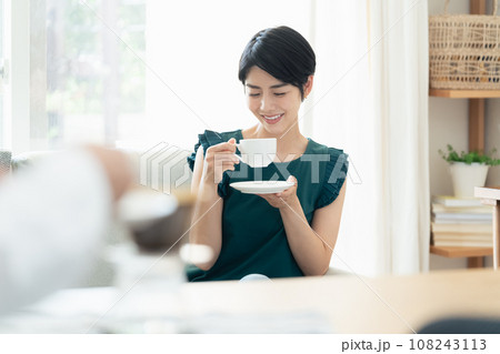 リビングで会話をしながらコーヒーを飲む女性 リビングで会話をしながらコーヒーを飲む女性 108243113