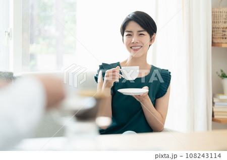 リビングで会話をしながらコーヒーを飲む女性 リビングで会話をしながらコーヒーを飲む女性 108243114