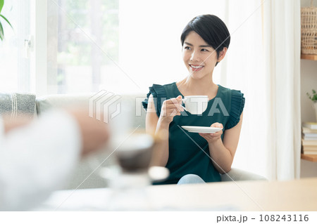 リビングで会話をしながらコーヒーを飲む女性 リビングで会話をしながらコーヒーを飲む女性 108243116