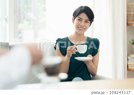 リビングで会話をしながらコーヒーを飲む女性 リビングで会話をしながらコーヒーを飲む女性 108243117