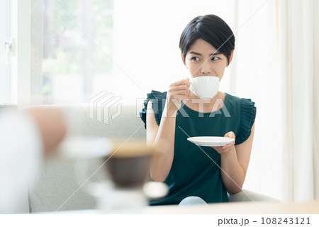 リビングで会話をしながらコーヒーを飲む女性 リビングで会話をしながらコーヒーを飲む女性 108243121