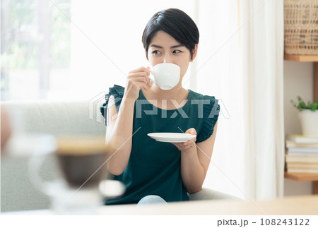 リビングで会話をしながらコーヒーを飲む女性 リビングで会話をしながらコーヒーを飲む女性 108243122