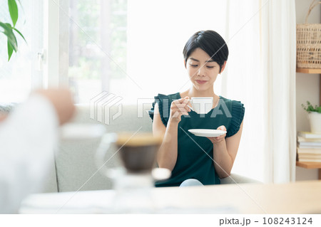 リビングで会話をしながらコーヒーを飲む女性 リビングで会話をしながらコーヒーを飲む女性 108243124
