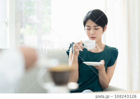 リビングで会話をしながらコーヒーを飲む女性 リビングで会話をしながらコーヒーを飲む女性 108243126