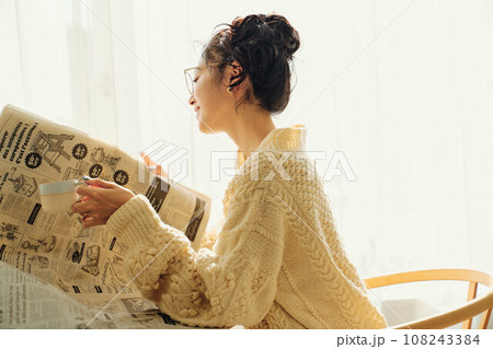 カフェで新聞を読みながら談笑する女性 108243384