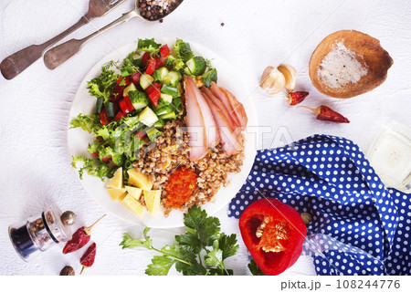 A plate of buckwheat with meat, salad , cheese on white backgrond A plate of buckwheat with meat, salad , cheese on white backgrond 108244776