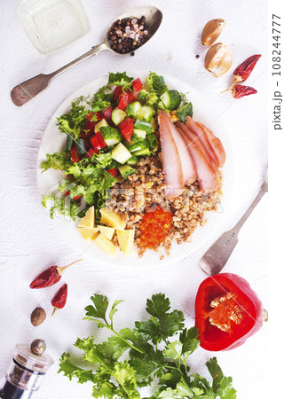 A plate of buckwheat with meat, salad , cheese on white backgrond A plate of buckwheat with meat, salad , cheese on white backgrond 108244777
