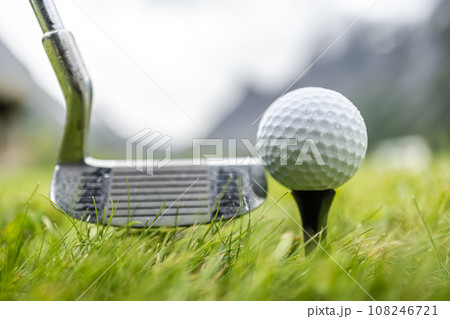 Golf ball on tee in front of driver 108246721