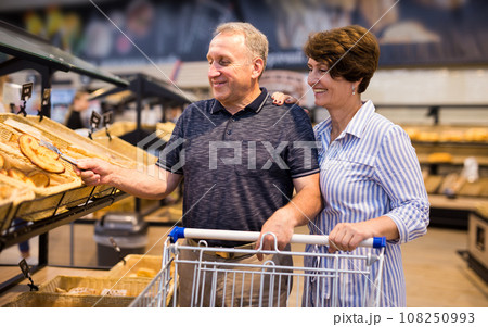Elderly couple buys bread and baking in grocery section of supermarket Elderly couple buys bread and baking in grocery section of supermarket 108250993