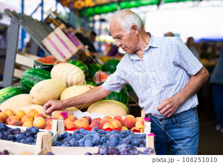 Retired european man buying plums peaches nectarine in market Retired european man buying plums peaches nectarine in market 108251010