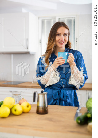 Woman dressed in a housecoat prepares coffee in the kitchen 108251011