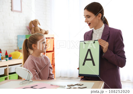 Speech therapist working with little girl in office 108252020