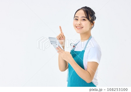 電卓を使うエプロン姿の若い主婦 108253100