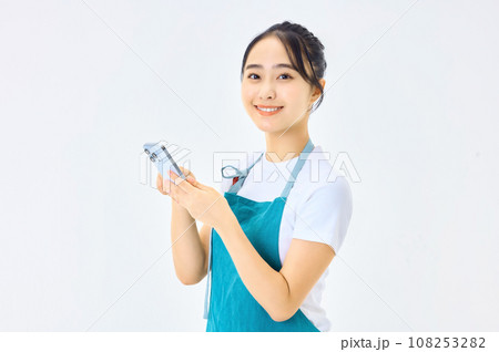 電卓を使うエプロン姿の若い主婦 108253282