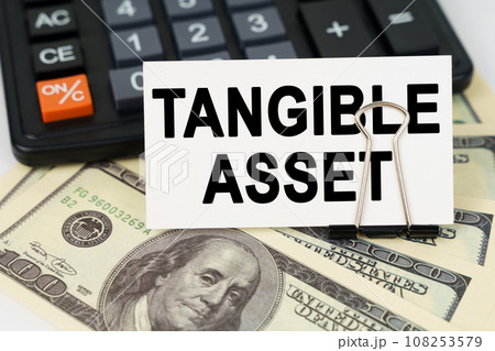 On the dollars there is a calculator and a business card with the inscription - tangible asset 108253579