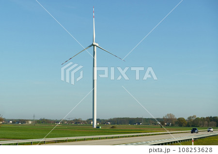 Wind turbine of a wind power plant standing along the road, against the background of a blue sky. Wind turbine of a wind power plant standing along the road, against the background of a blue sky. 108253628
