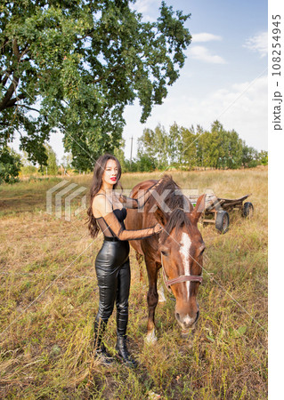 Beautiful young caucasian woman standing near the horse. Beautiful young caucasian woman standing near the horse. 108254945