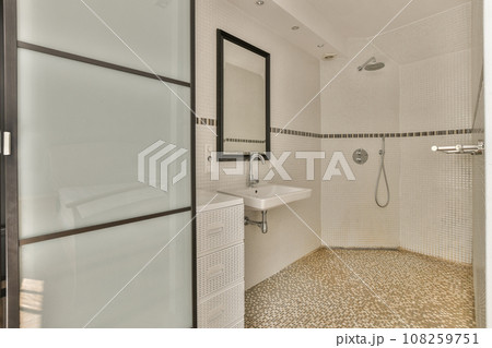 a bathroom with white tile and black trim on the shower door, sink and toilet in the background is tiled 108259751
