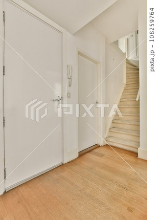 an empty room with white walls and wood flooring on the right side, there is a staircase leading up to the second floor an empty room with white walls and wood flooring on the right side, there is a staircase leading up to the second floor 108259764