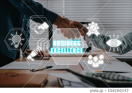 Business excellence concept, Business team making handshake with his partner in office desk with business excellence icon on virtual screen. Business excellence concept, Business team making handshake with his partner in office desk with business excellence icon on virtual screen. 108260147