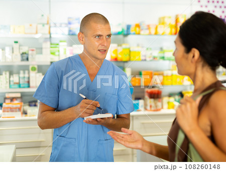 Male doctor writing recipe for client in drugstore 108260148