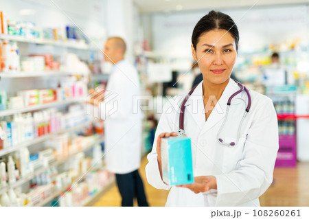 Oriental female pharmacist standing in salesroom of drugstore Oriental female pharmacist standing in salesroom of drugstore 108260261