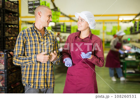 Manager and hired employee communicate during breaks between work in fruit warehouse 108260531